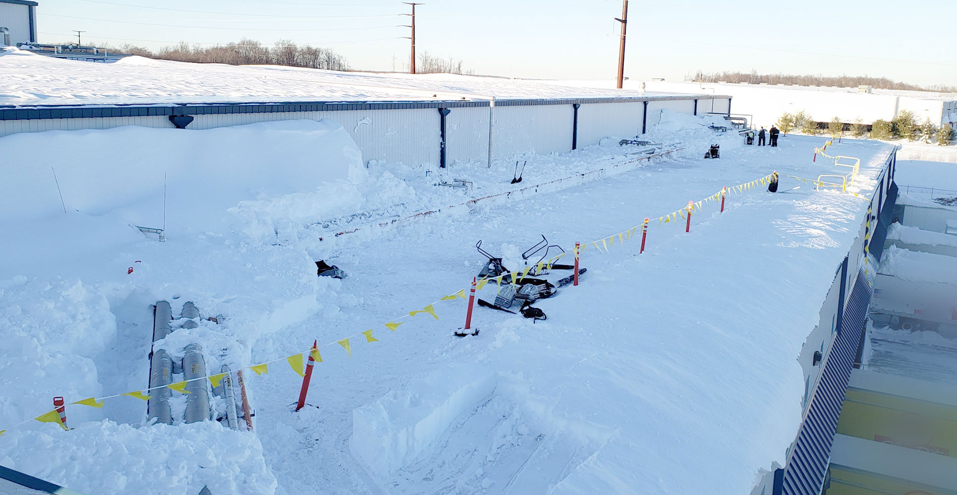 commercial roof covered in snow in process of snow removal by CentiMark