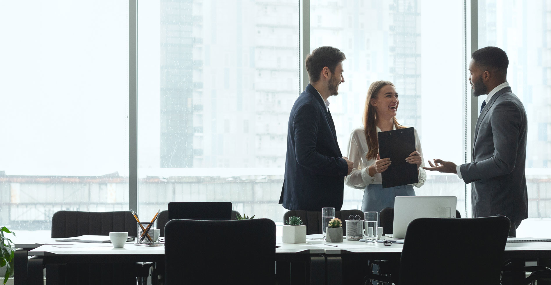 three business professionals in a glass building discussing a project