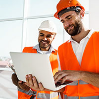 two smiling engineers looking at laptop